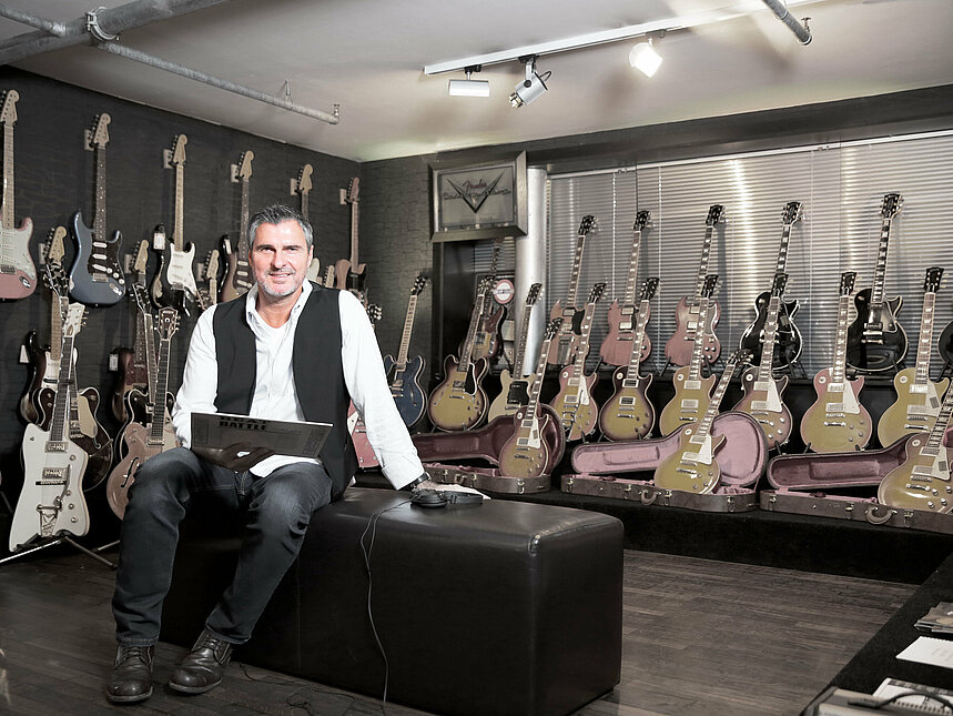 Michael Roth in einem Raum voll mit Gitarren