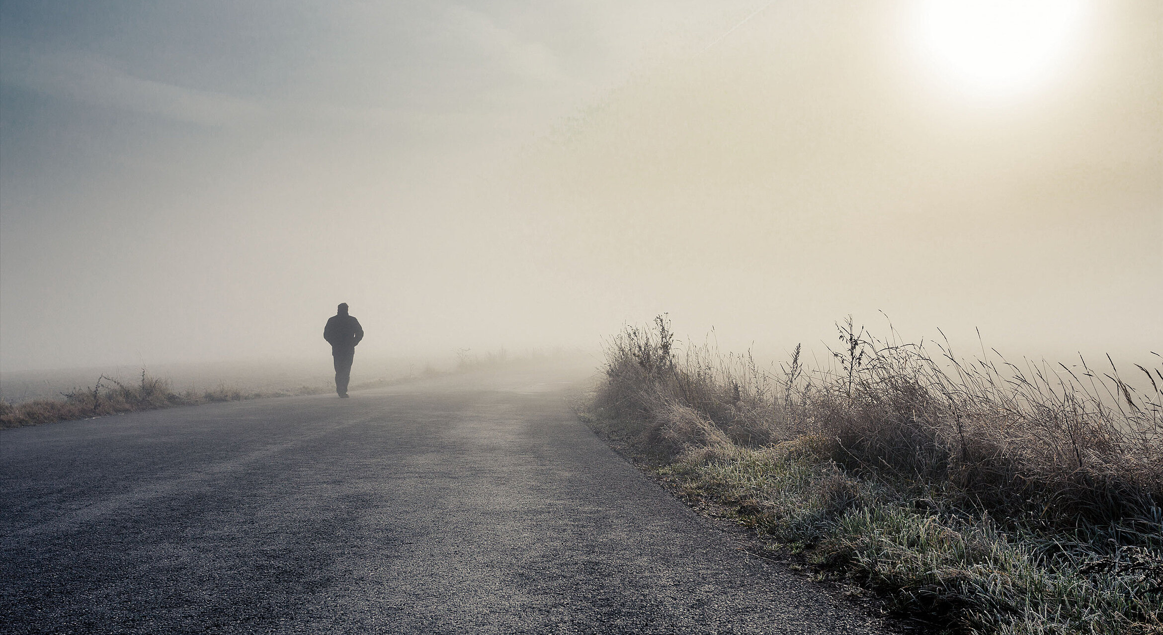 Mann geht auf einer Straße im Nebel